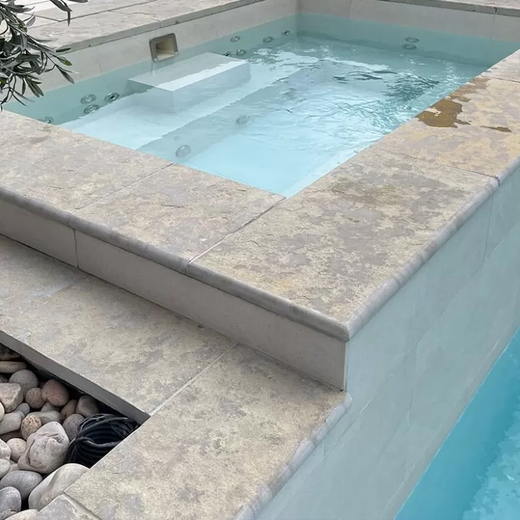 A waterfall feature coming out of a raised spa pool and into a swimming pool
